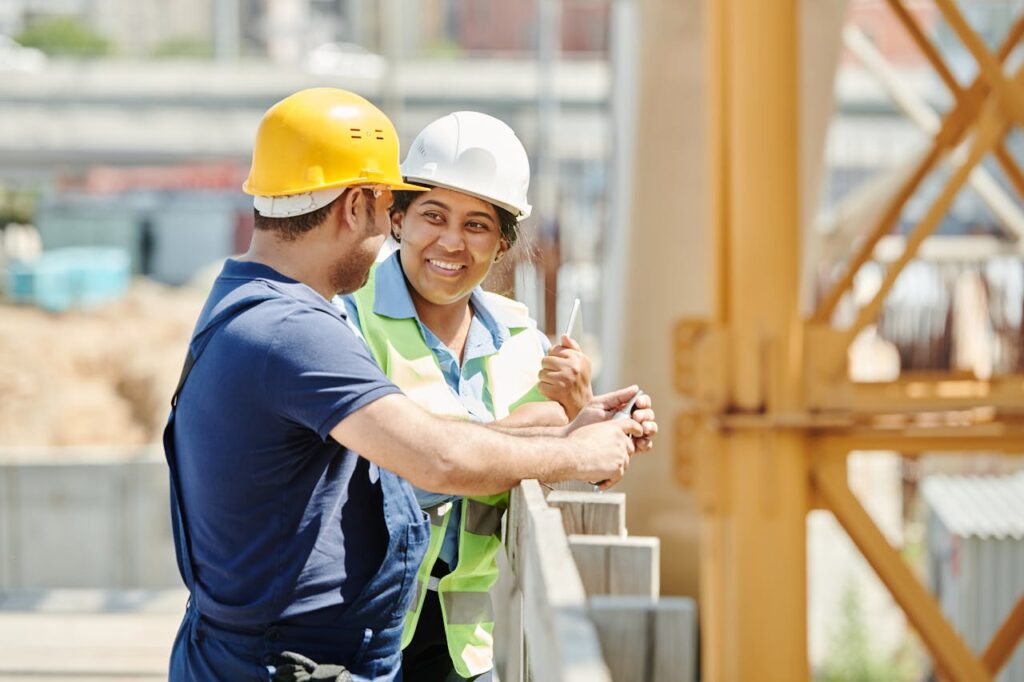 Male and female construction workers discussing plans at a building site.